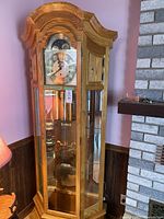 Full view of the grandfather clock showing the wooden finish, clock face, glass panels, and overall height.
