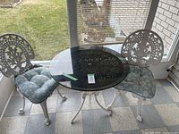 Full view of the metal patio set with table and two chairs with cushions
