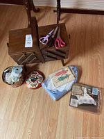 Photo showing the vintage wooden sewing box, three pairs of scissors, two decorative tins with sewing supplies, a pack of sewing patterns, and packaged fabrics.