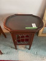 Full view of vintage wooden accent table with cupboard and removable tray top, showing design and condition.