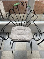 Full view of vintage black metal fan style chair with light patterned cushioned seat, showing design and structure.