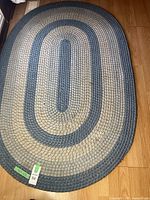 Oval-shaped braided rug laid on wood floor, showing full length and pattern.
