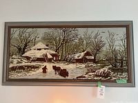 Full view of framed crewel embroidery winter scene artwork with houses, trees, horses and person.