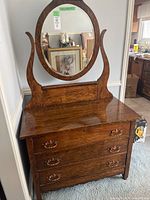Frontal view of the vintage dresser showing the removable top piece with an oval mirror and three drawers with metal handles.