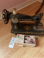 Vintage black Singer sewing machine with spool and boxed attachment in front