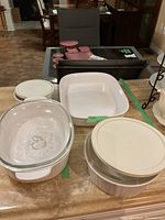 Photo showing 4 CorningWare ceramic ovenproof dishes with lids, arranged on kitchen counter, highlighting different shapes and lids.