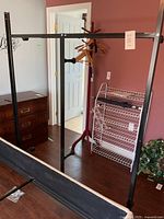 Full view of the black adjustable metal bedframe in a room, showing its structure and wheels at base.