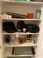 Shelf with baking sheets, orange storage tin, glass jars