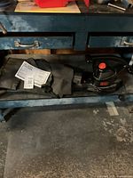 Photo showing Black & Decker blower vac and leaf collection bag on a bench.