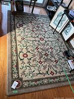 Full view of beige floral carpet on hardwood floor, showing design and condition.