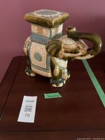 Front and side view of 11 inch ceramic elephant statue with decorative saddle and platform on back.