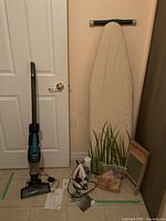 Bissell vacuum, iron, ironing board, wooden washboard, glass container with clothespins, and a faux plant shown together