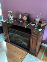 Full view of the electric fireplace in a dark brown wooden cabinet with side cupboards and media storage. Decorative items on top not included.