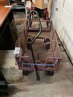Front view of the metal garden wagon showing the handle and mesh sides with wheels underneath