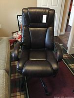 Front view of the dark brown pleather high back office chair showing padded armrests, cushioned seat, and five-legged base with casters.