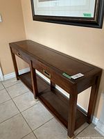 Side perspective of sofa back table showing two drawers with brass handles and lower caned shelf
