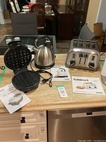 Full view of toaster, kettle, waffle maker on counter with instruction manuals