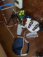 Overview of lot showing various medical aids on floor including weights, bed rail, heating pad, straps, knee braces and grab stick
