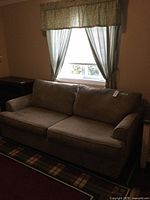 Full view of the light green pull-out sofa bed placed in a room with window behind, showing its overall shape and fabric texture