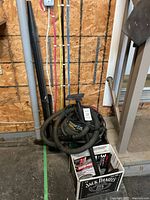 Full view of Shop-Vac with hose coiled on top, some attachments visible, placed on floor near wall with colored pipes.
