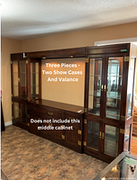 Wide shot showing the two end showcase cabinets and connecting valance above, placed against wall with the middle cabinet missing as noted.