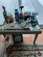 Photo of wood patio table showing various outdoor supplies arranged on top and two garden books underneath.