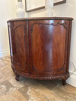 Front view of cabinet showing curved doors, carved trim and bracket feet.