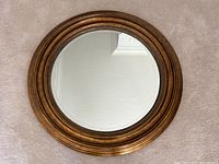 Front view of round antique style gold painted wood mirror showing full frame and glass surface