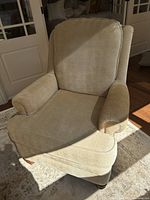 Front view of beige upholstered armchair showing loose back and seat cushions, and the darker right arm.