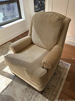 Front-left angle view showing high back, armrests, loose cushions and wooden legs with beige herringbone upholstery under natural light