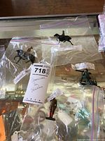 Plastic bagged American tin soldiers displayed on a glass surface, showing two mounted and one standing figurine.