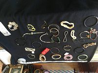Full view of 26 assorted bracelets laid out on black cloth with ruler showing size.