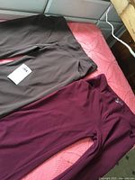 Two pairs of brown and burgundy stretch pants laid flat on surface showing front sides