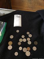 Multiple foreign coins displayed on a black fabric background with a lot tag.