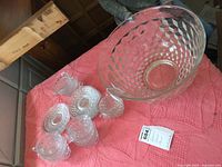 Punch bowl with cups and saucers displayed on red textured fabric