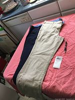 Two pairs of Nautica jeans laid flat on a surface showing tan and navy colors.