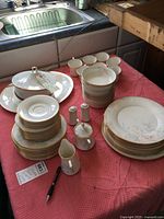 Full view of the Noritake Sweet Surprise China set arranged on a pink cloth with plates, cups, saucers, platters, casserole, and serving pieces.