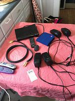 Sony DVD player, two universal remote controls, two sets of Logitech powered speakers, and cables arranged on a pink cloth-covered surface