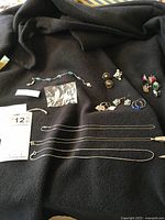 Jewelry laid out on black fabric including necklaces, earrings, and bracelet, showcasing lot contents