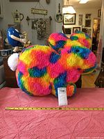 Front and side view of the large tie dyed stuffed bunny placed on a pink surface with a measuring tape showing dimensions and a Lot tag visible.