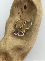Pair of antique 10 karat gold heart-shaped amethyst earrings displayed on a wooden surface.