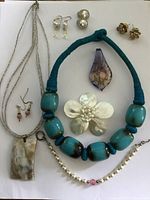 Photo of the full jewelry group laid out on white background including necklaces, bracelets, earrings, brooches, and pendants.