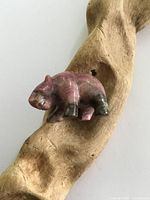 Photo of the small carved stone grizzly bear figurine on a textured wood surface showing front and side views.