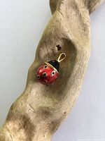 Pendant shown resting on brown wood with an irregular carved shape to highlight size and design.