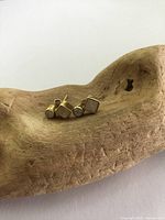 Front angled view of two gilt sterling silver stud earrings with moonstone and quartz stones, placed on a natural wood carved dish.
