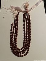 Full view of the four-strand gold freshwater pearl necklace laid flat showing beads and length.