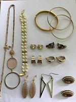Photo of entire group of costume jewelry laid flat on white background showing necklace, bracelet, bangles, and earrings.