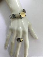 Mid Century Modern style costume jewelry ring and bracelet set displayed on a mannequin hand, showing geometric design with brushed gold-tone and translucent smoky accents on silver-tone metal.