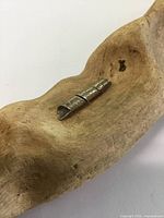 Image showing top angled view of hollow silver scroll pendant with spiral etched design on wooden background