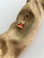 Winnie the Pooh gold plated charm resting on curved wood, showing front of charm in natural light.